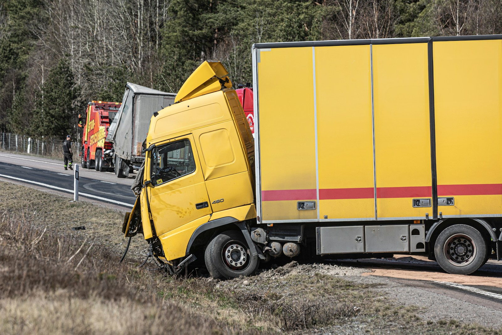 A yellow semi-truck is in a roadside accident.